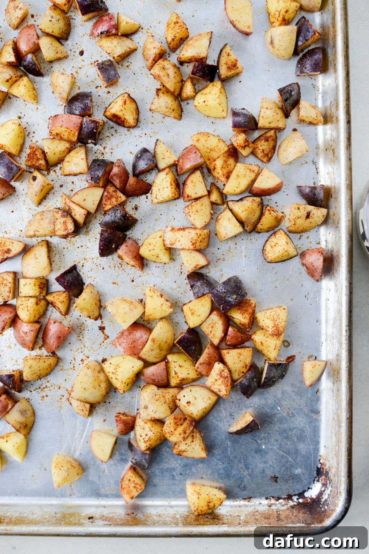 Easy Turkey Taco Breakfast Scramble Meal Prep 6 Close-up of baby potatoes coated in olive oil and taco spices on a baking sheet, ready to go into the oven.