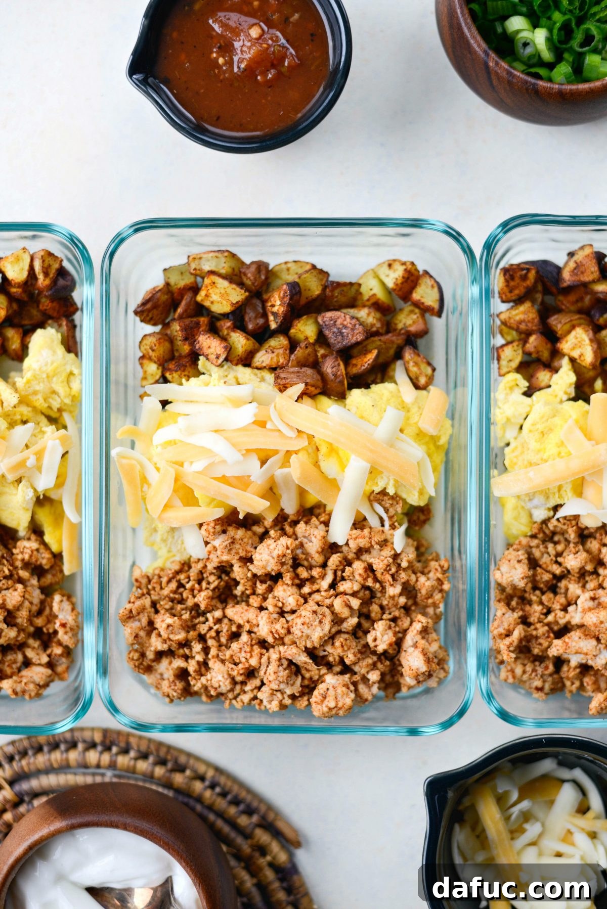Easy Turkey Taco Breakfast Scramble Meal Prep 9 Adding turkey taco meat and topping scrambled eggs with shredded cheese in a meal prep container.