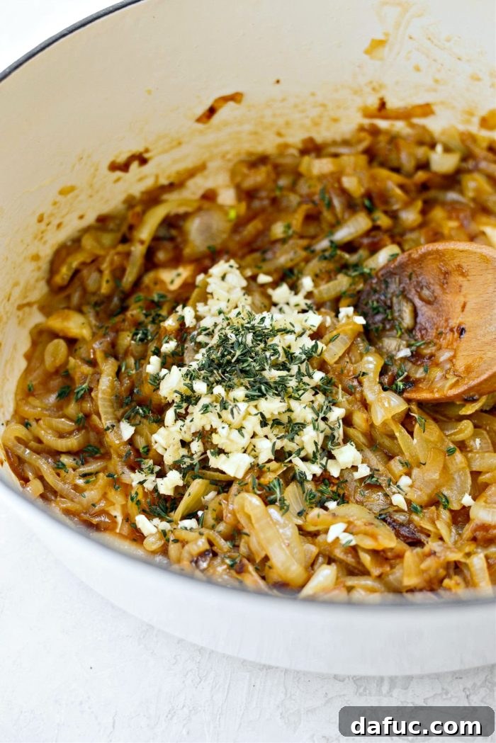 Creamy French Onion Chowder 10 Minced garlic and fresh thyme being added to caramelized onions in a pot