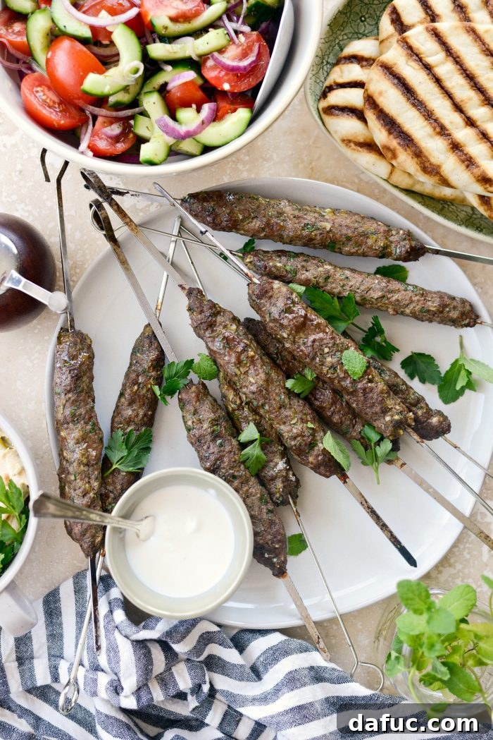 A baking sheet filled with perfectly cooked, golden brown lamb kofta skewers, fresh out of the oven