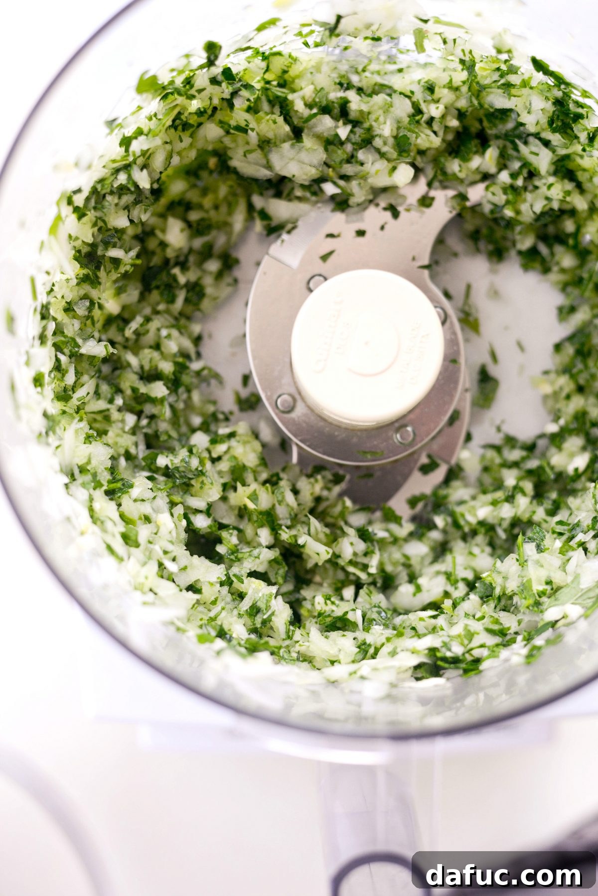 Finely minced parsley, mint, onion, and garlic in a food processor, ready for the kofta mixture