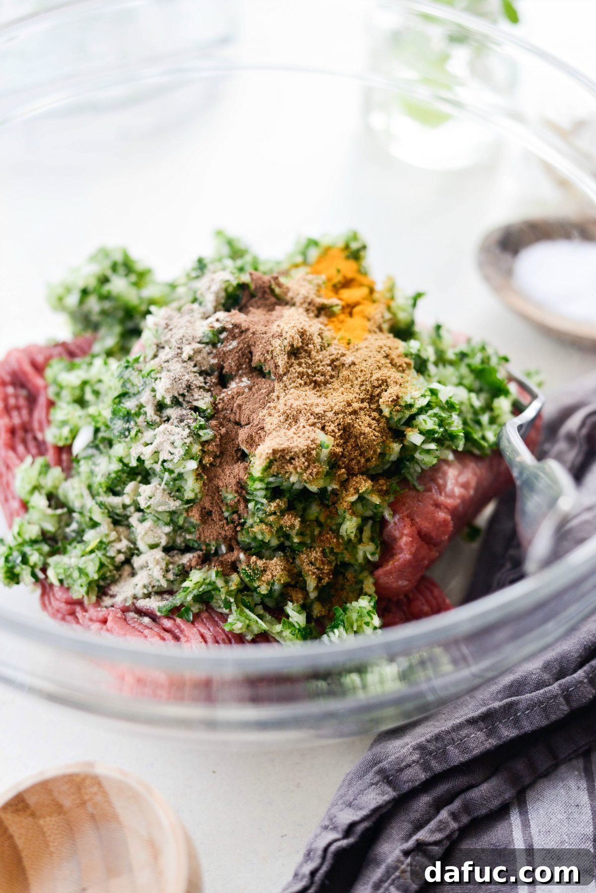 Hand sprinkling rich Middle Eastern spices onto the ground meat and herb mixture