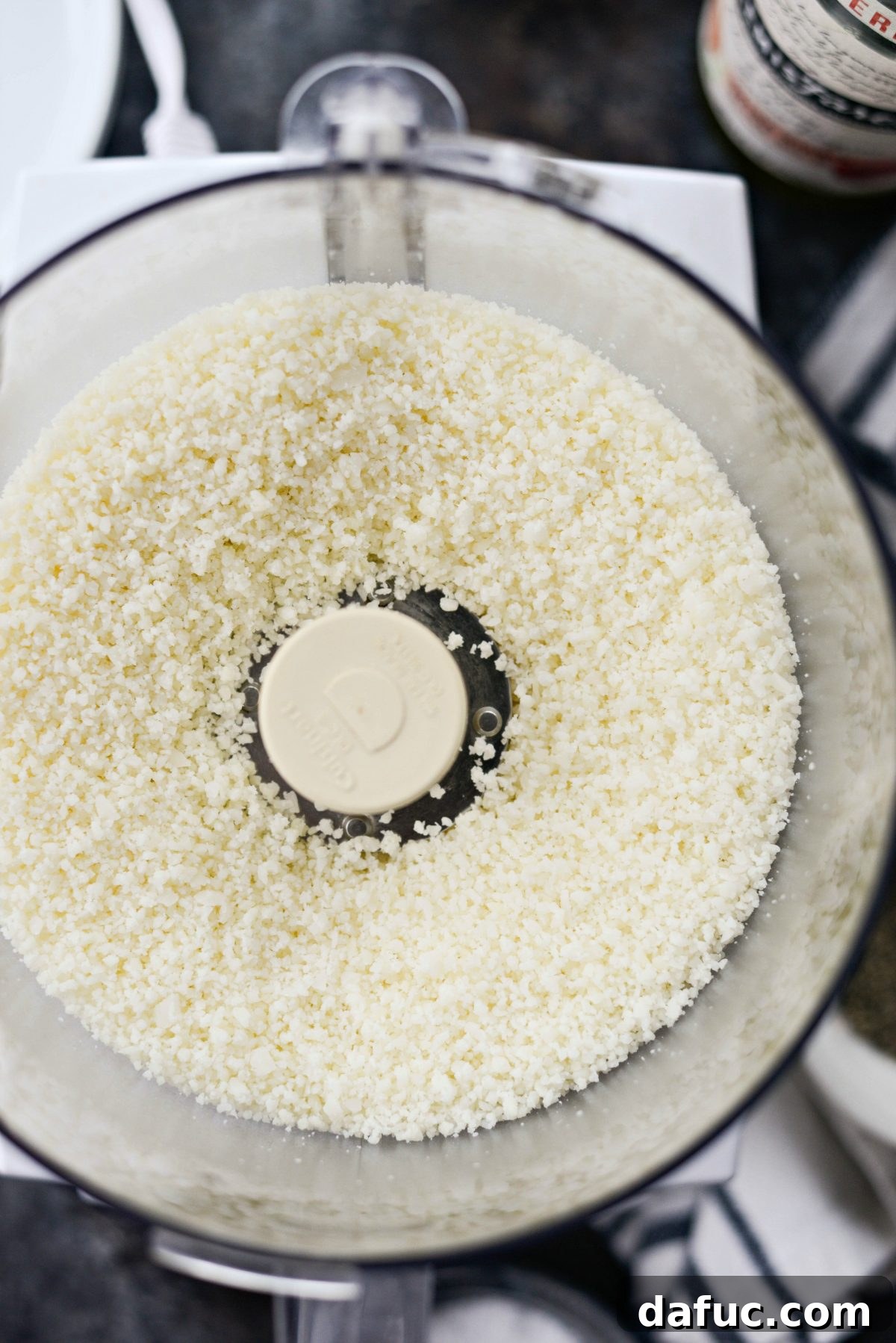 Pecorino Romano cheese being finely grated in a food processor, essential for a smooth sauce.