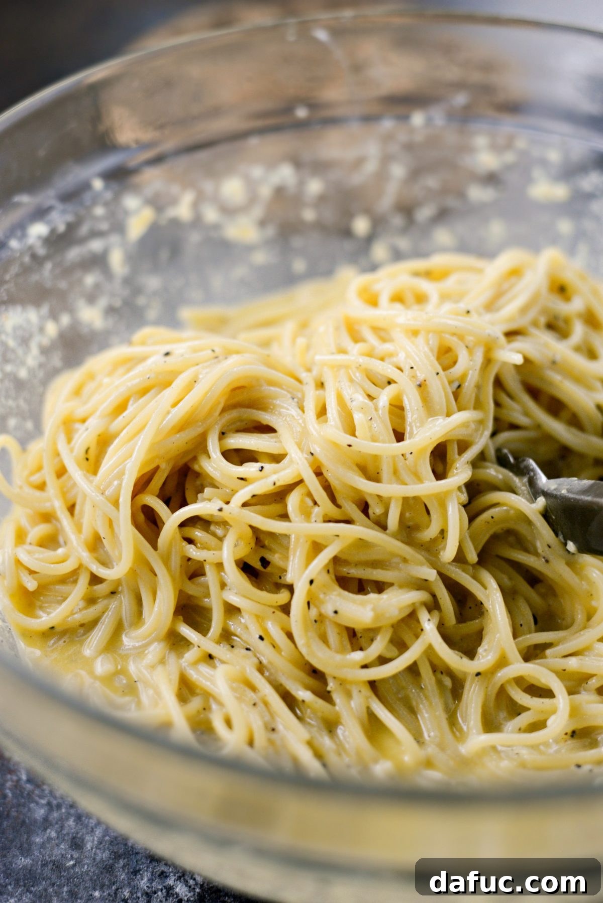 Reimagined Cacio e Pepe Carbonara 10 Tossing the Cacio e Pepe Carbonara vigorously in the bowl to coat all the spaghetti strands with the creamy sauce.