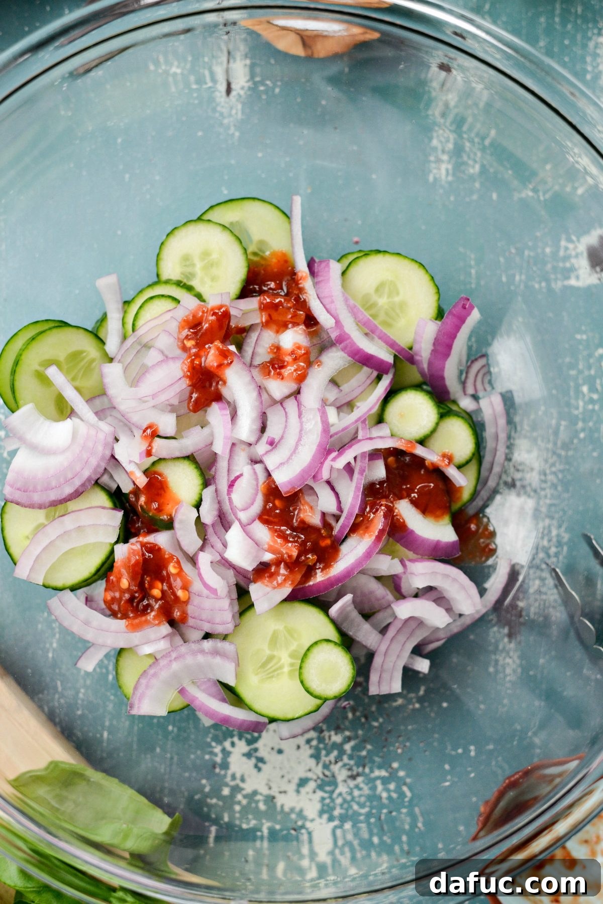 Sliced cucumbers, red onions, and sambal oelek added to the cooled vinegar syrup