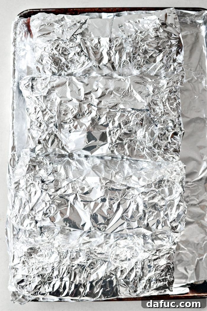Wrapped ribs on a foil-lined baking sheet, ready for the oven