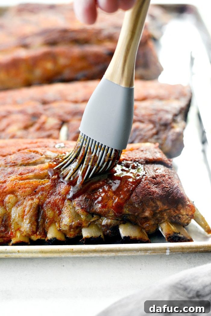 Brushing homemade BBQ sauce onto oven-baked ribs