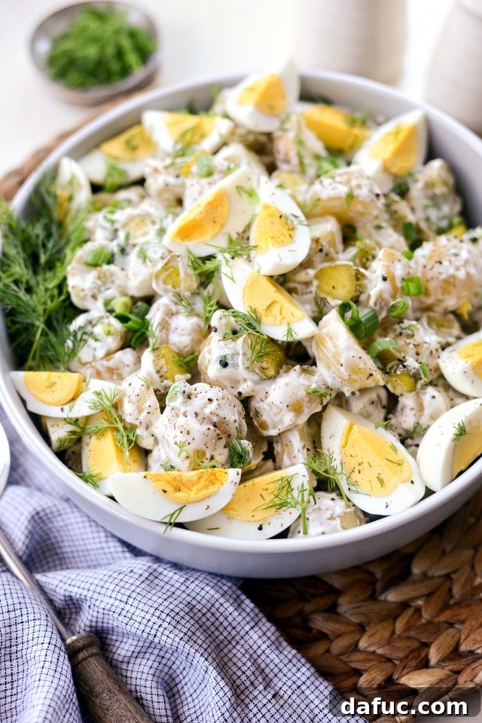 Pucker-Up Potato Salad 14 A large serving bowl filled with Dill Pickle Potato Salad, garnished with hard-boiled eggs, fresh dill, and black pepper, ready for a potluck.