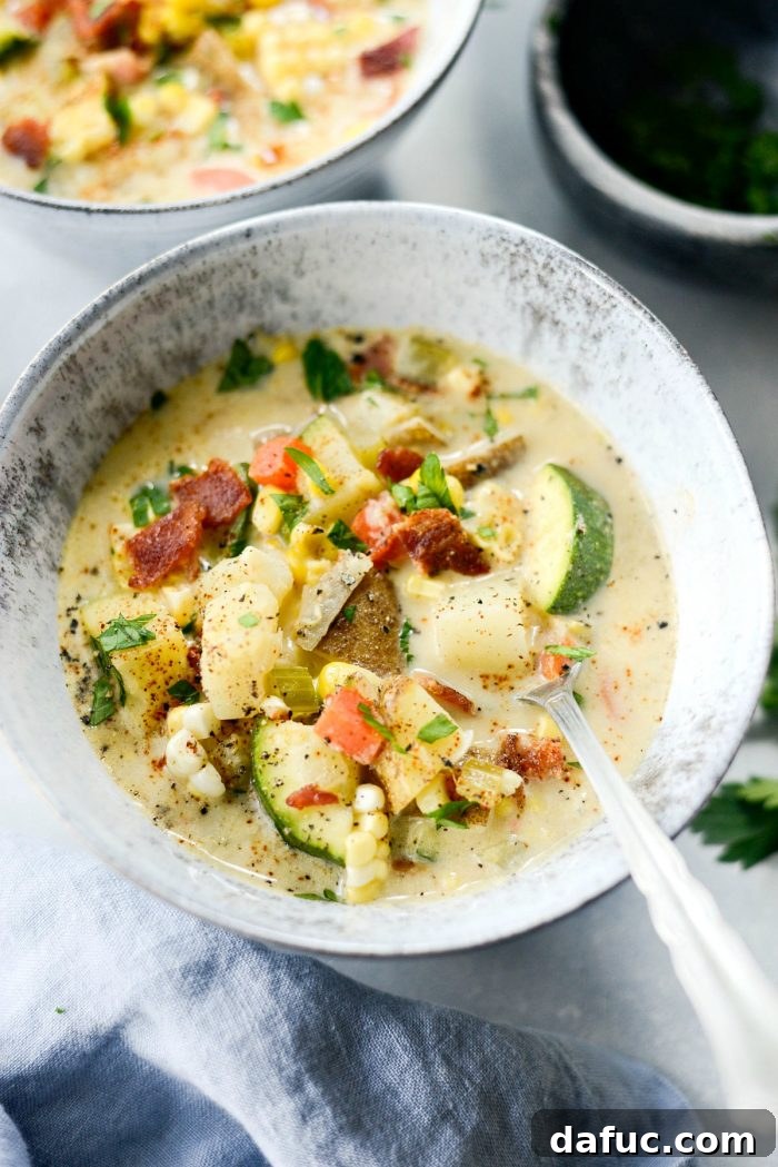Golden Harvest Corn and Zucchini Chowder 10 A beautiful overhead shot of a serving of Summer Corn and Zucchini Chowder in a bowl, with a spoon, highlighting its creamy texture and visible vegetable pieces.
