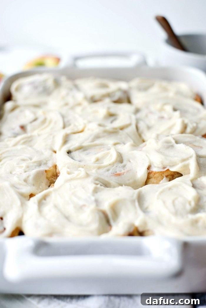 Icing being spread onto warm cinnamon rolls. SimplyScratch.com