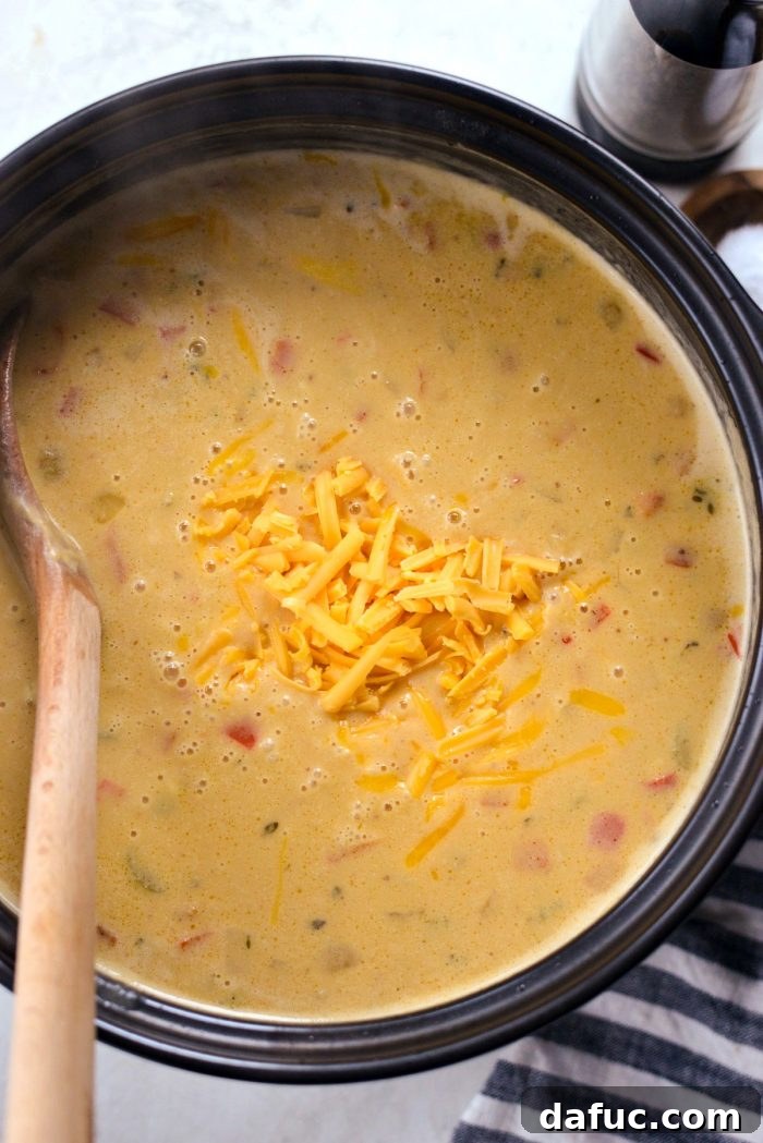 Harvest Ale & Creamy Cheddar Pumpkin Soup 15 Shredded extra sharp cheddar cheese being stirred into the hot pumpkin beer cheese soup off the heat.