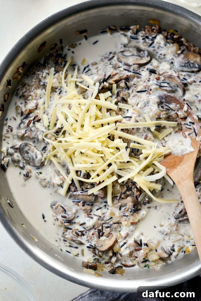 Hearty Mushroom Wild Rice Bake 10 Shredded Gruyere cheese being stirred into the mushroom and wild rice mixture.