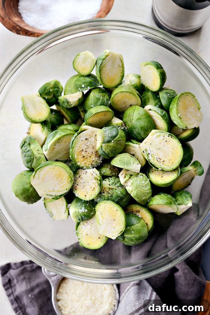 Brussels sprouts tossed with olive oil, salt, and pepper in a bowl.