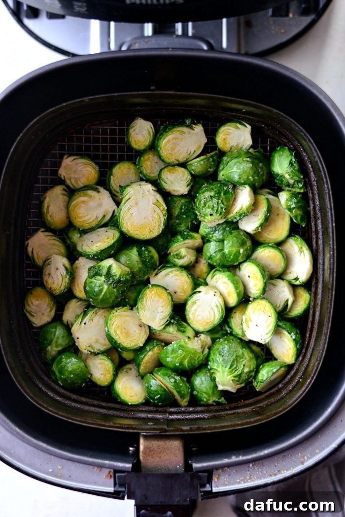 Shaking the air fryer basket to ensure even cooking of Brussels sprouts.