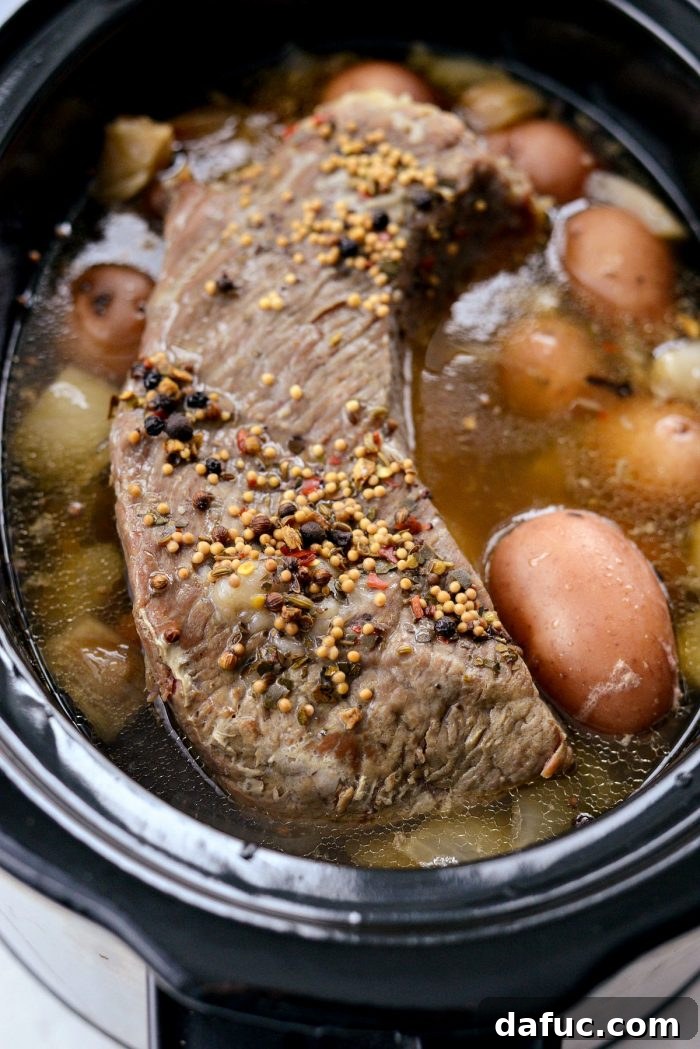 Effortless Slow Cooker Corned Beef and Cabbage 11 Removing cooked corned beef brisket from slow cooker with tongs