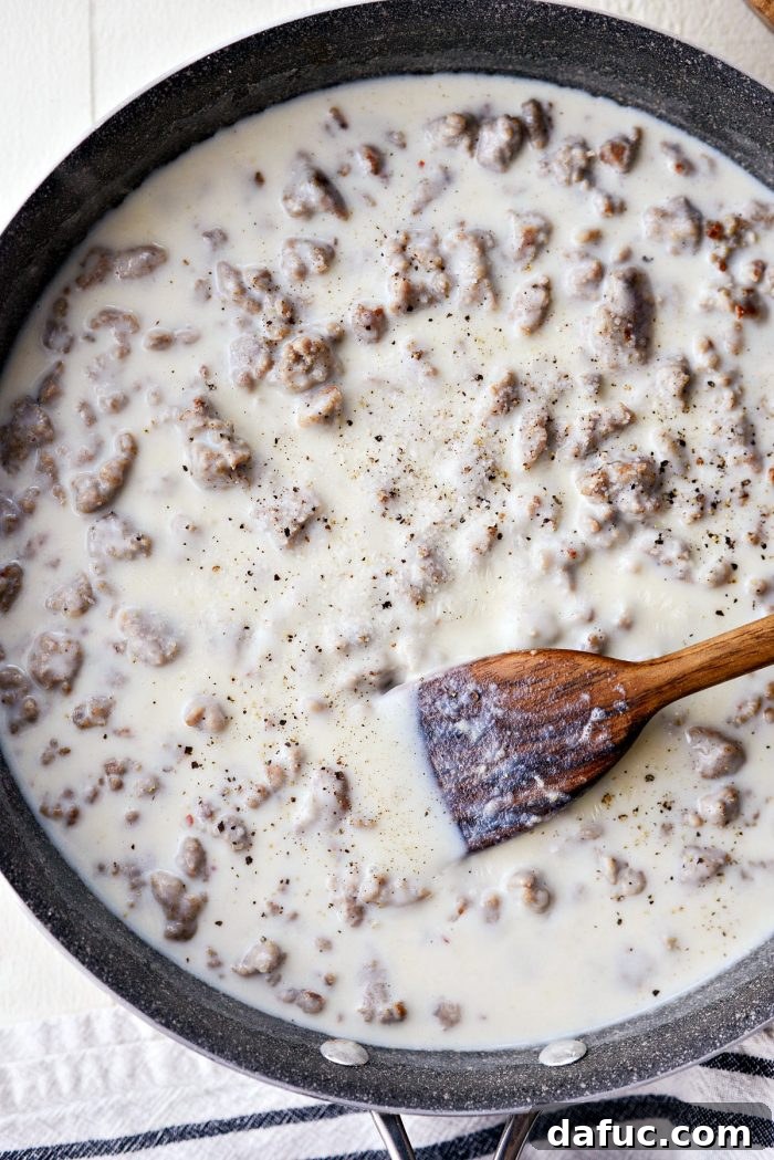 Milk being poured into the skillet with turkey sausage and flour, beginning the gravy-making process.