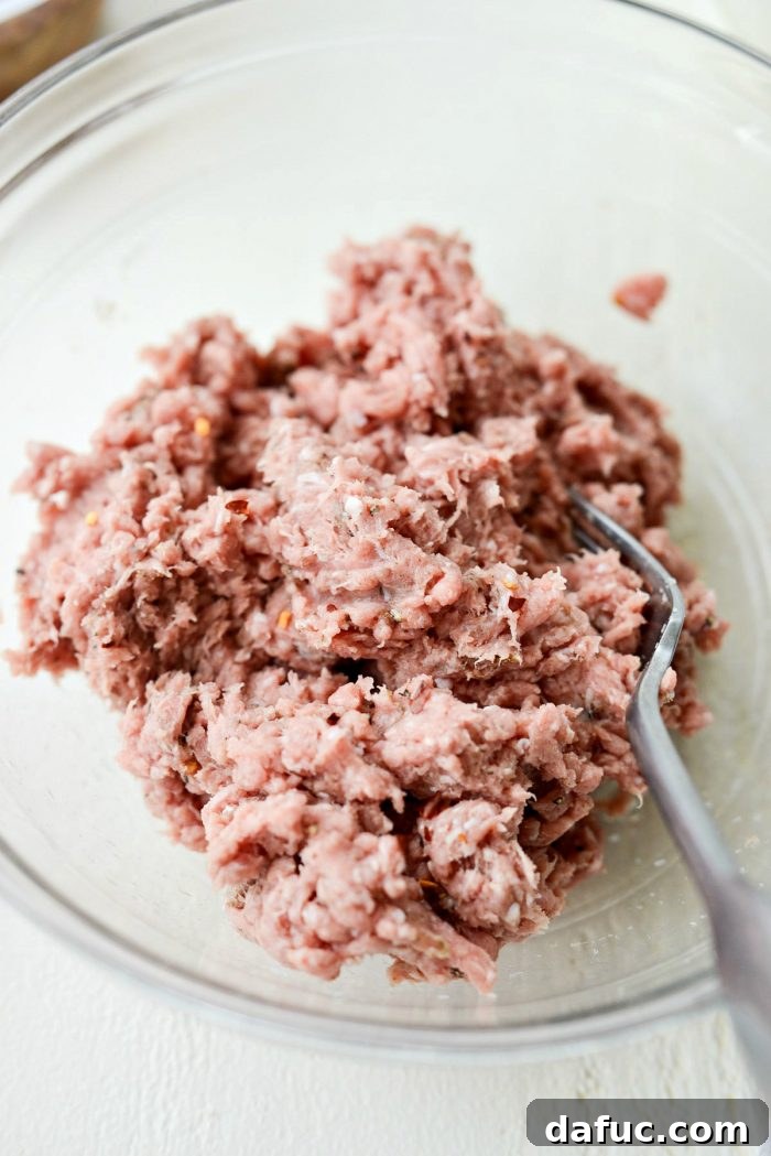 Ground turkey mixed with a medley of herbs and spices in a mixing bowl, ready to be cooked for breakfast gravy.