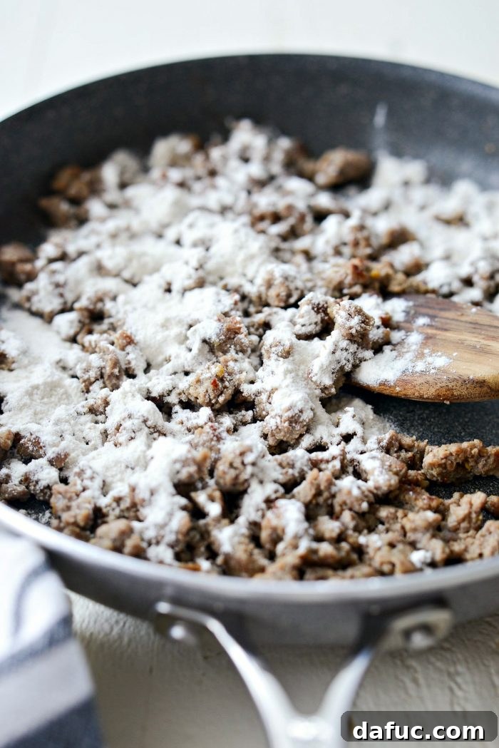 Perfectly browned and crumbled ground turkey sausage in a skillet, indicating it's ready for flour to be added.