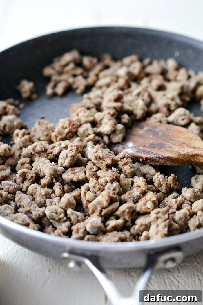 Three tablespoons of unbleached all-purpose flour sprinkled over browned turkey sausage in a skillet.