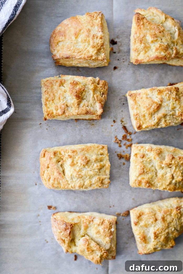 Cloud-Like Greek Yogurt Biscuits 14 A rustic wooden board piled high with golden-brown Greek Yogurt Biscuits, some split open, some whole.