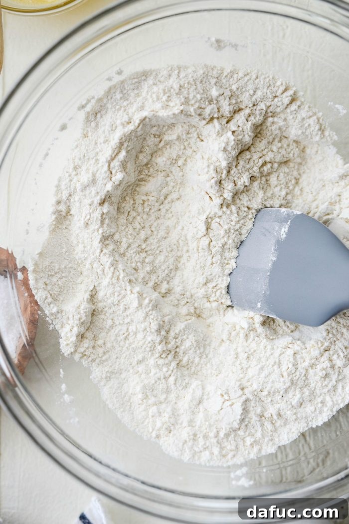 Cloud-Like Greek Yogurt Biscuits 5 Dry ingredients - flour, baking powder, sugar, and salt - measured into a mixing bowl.