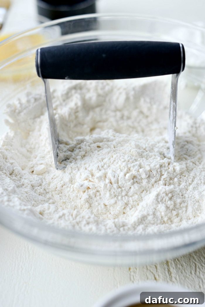 Cloud-Like Greek Yogurt Biscuits 7 Cold, cubed unsalted butter being added to the dry ingredients in a mixing bowl.