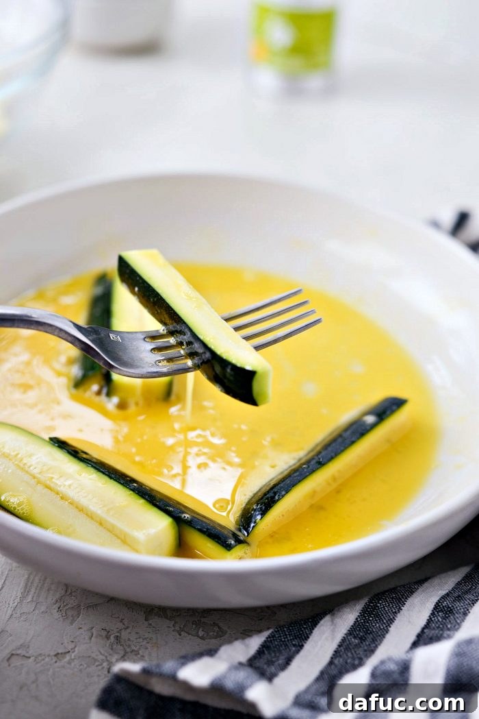 Crispy Air-Fried Zucchini Sticks 13 Excess egg dripping from zucchini fry held by a fork.