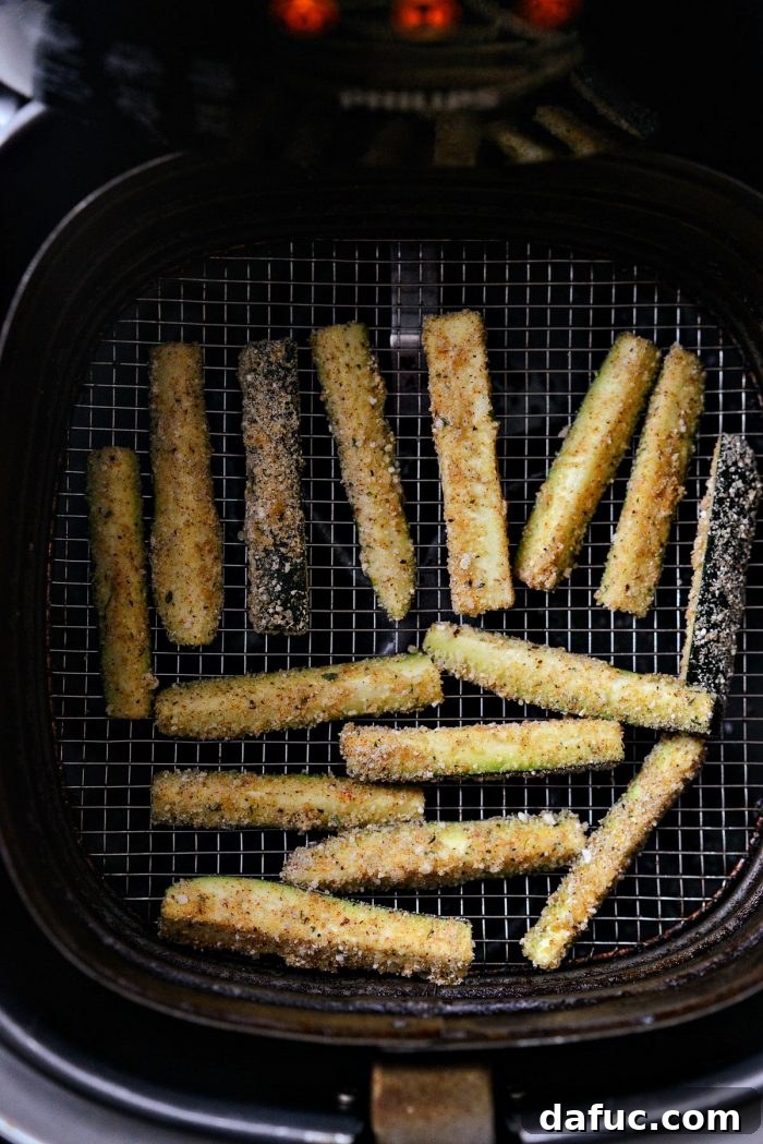 Crispy Air-Fried Zucchini Sticks 18 Uncooked zucchini fries neatly arranged in a single layer in the air fryer basket.