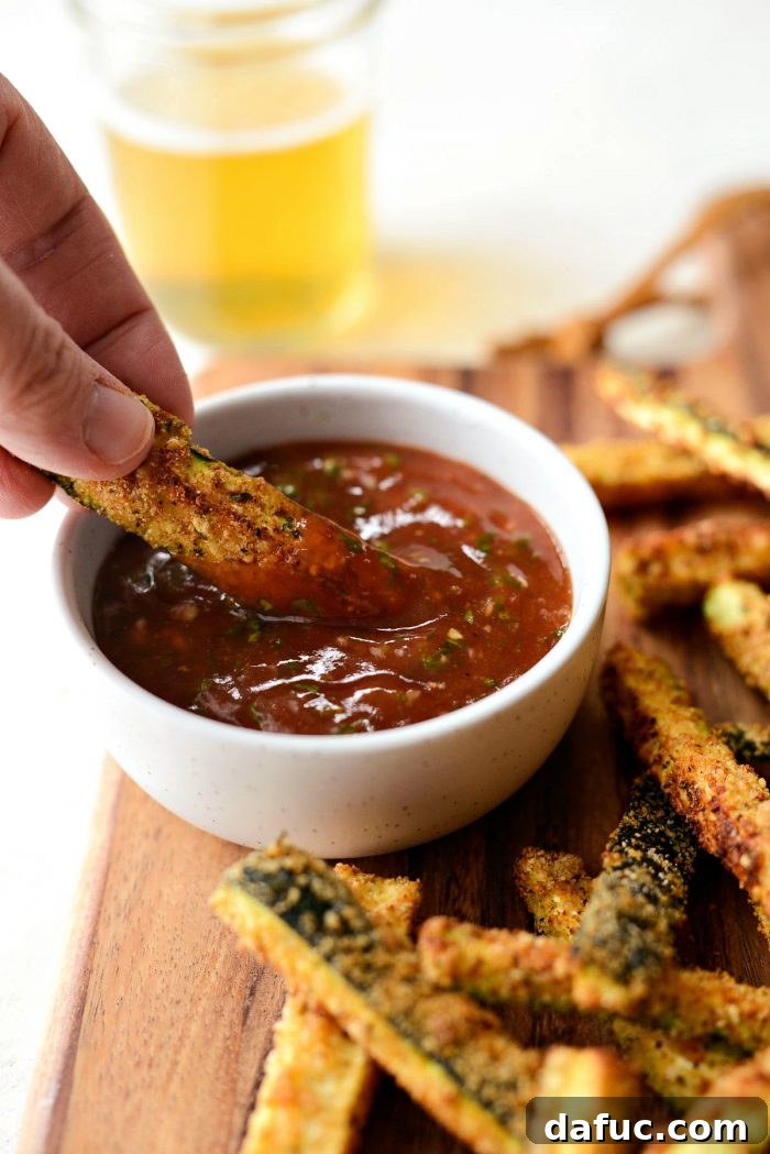 Crispy Air-Fried Zucchini Sticks 25 Detailed close-up of a crispy zucchini fry, highlighting its golden crust and delicious basil ketchup.