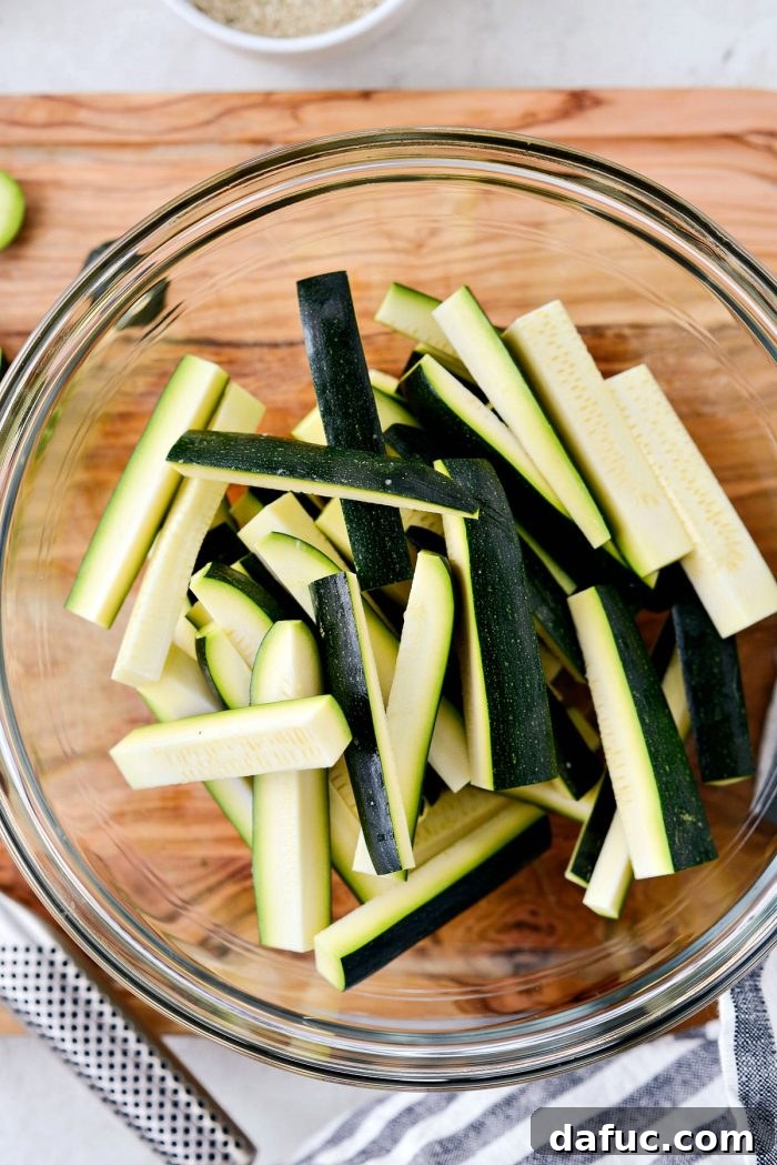 Crispy Air-Fried Zucchini Sticks 8 Glass bowl filled with freshly cut zucchini sticks, ready for breading.