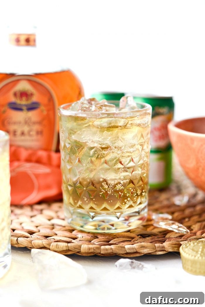 Lewis Peach Ginger Whiskey Infusion 3 Close-up of a clear textured glass showcasing the vibrant Lewis' Ginger Peach Whiskey Cocktail.