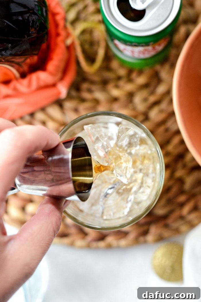 Lewis Peach Ginger Whiskey Infusion 7 Pouring 1 shot of peach whiskey over ice in a clear textured glass.
