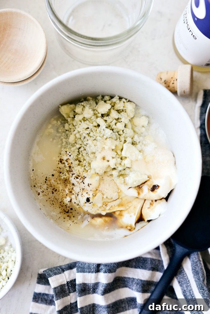 Tangy Greek Yogurt Blue Cheese Dressing 5 Measuring out ingredients into a white speckled bowl