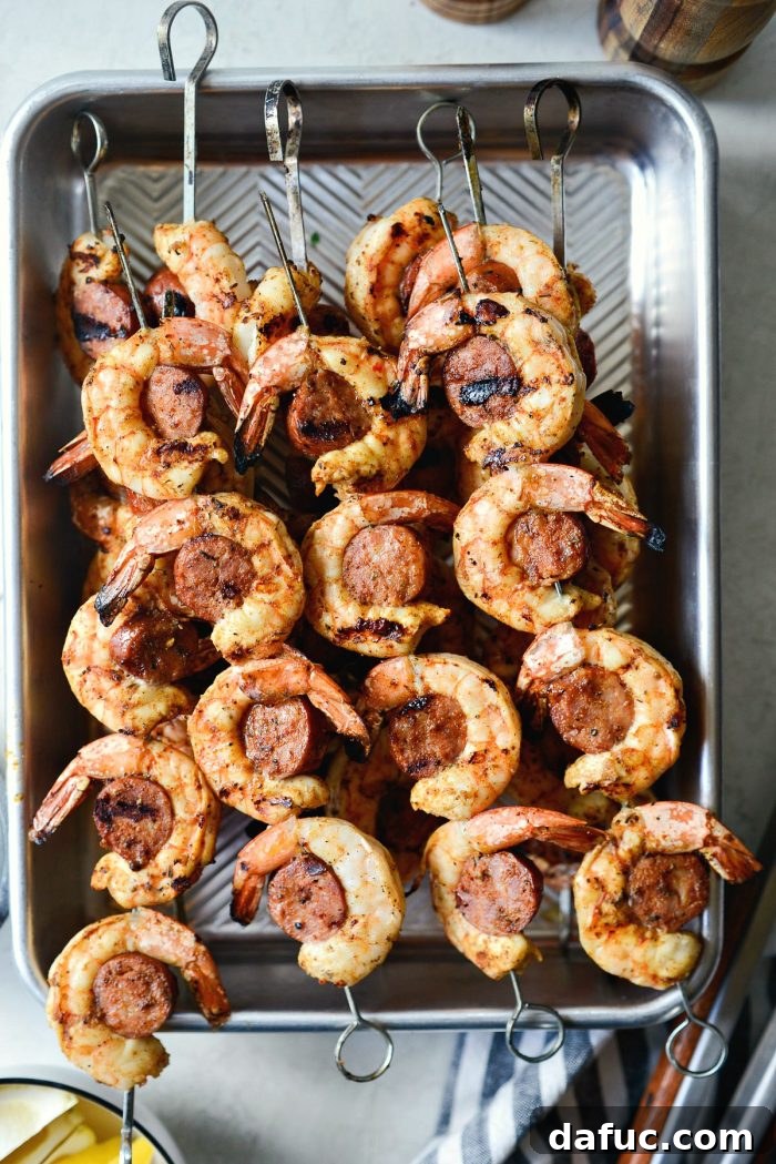 Grilled Cajun Shrimp and Andouille Skewers resting in a metal pan after being removed from the grill.