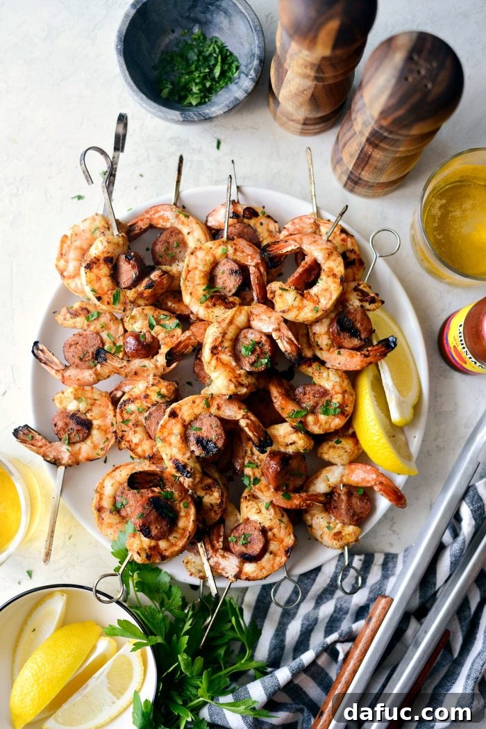 Grilled Cajun Shrimp and Andouille Skewers on a white plate, garnished with minced parsley for freshness.