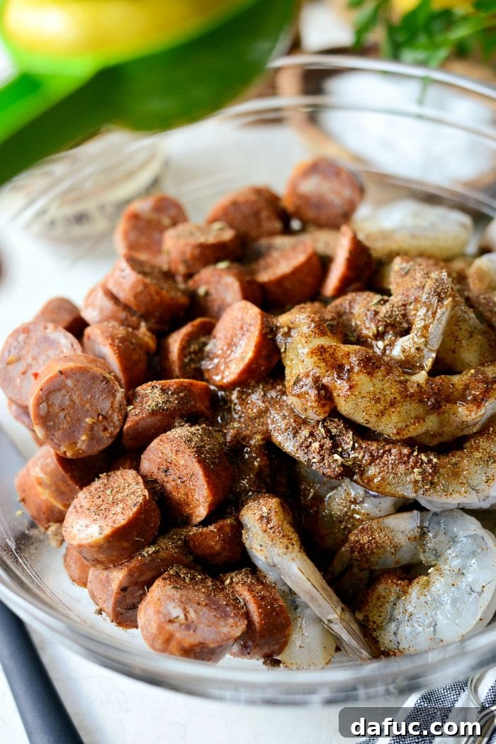 Squeezing fresh lemon juice into a bowl of shrimp and andouille, seasoned with Cajun spices and olive oil.