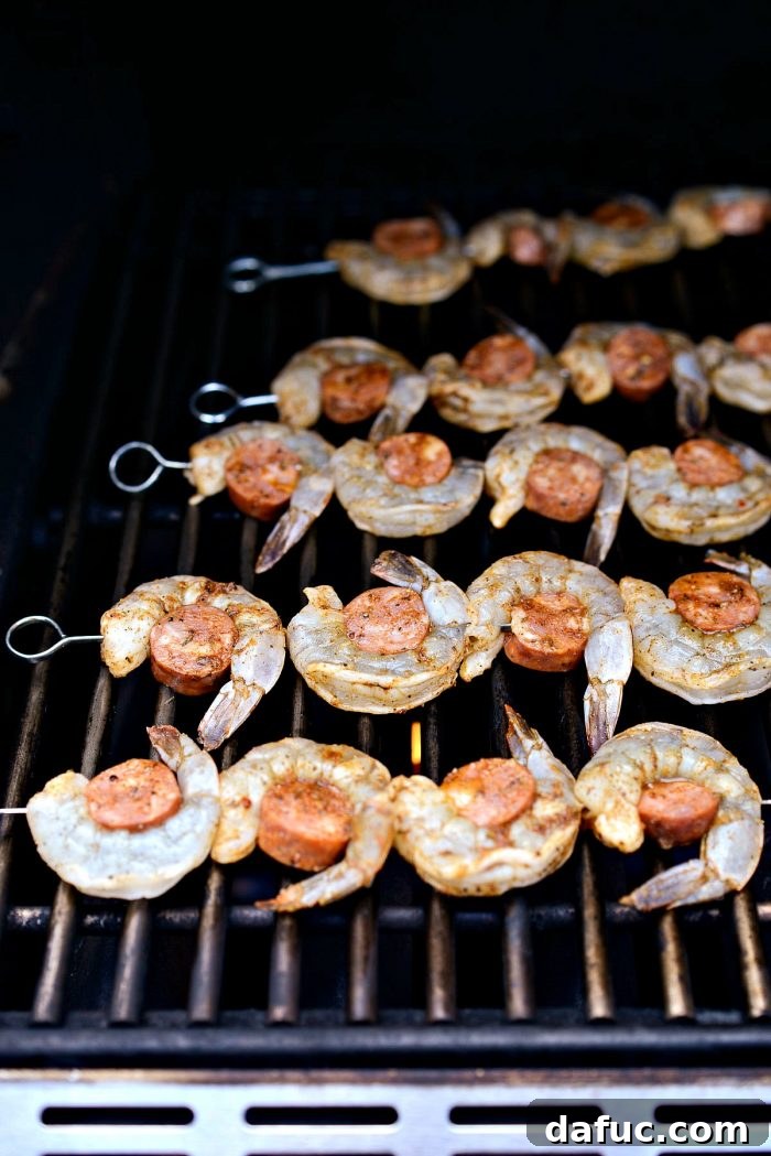 Cajun Shrimp and Andouille Skewers cooking on a hot grill, showing smoky charring.