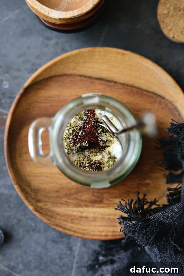 Smoky Chipotle Spice Mix 6 A metal spoon stirring the dry spice blend in a glass jar, ensuring even distribution.