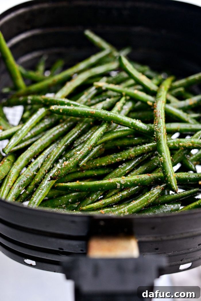 Crispy Air Fryer Green Beans 11 Seasoned green beans placed in the basket of an air fryer, ready to cook