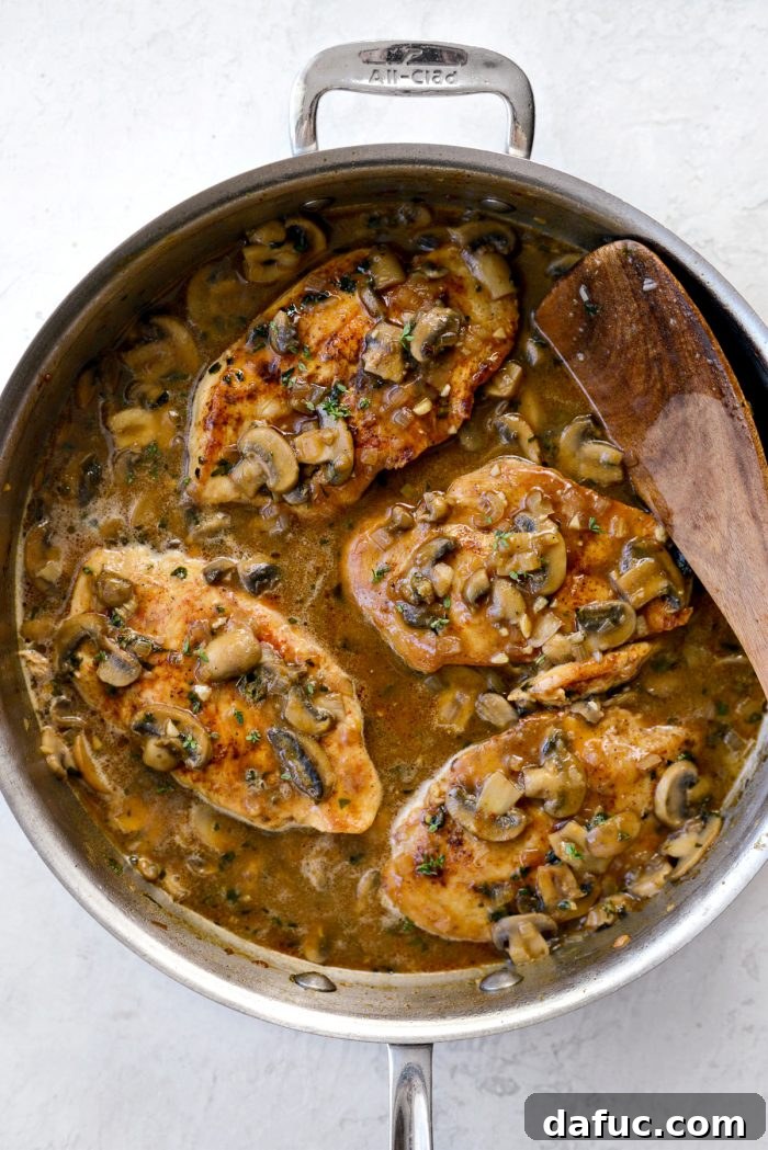 Lighter Chicken Marsala dish presented beautifully in a rustic skillet, garnished with fresh thyme and parsley sprigs, ready to serve.