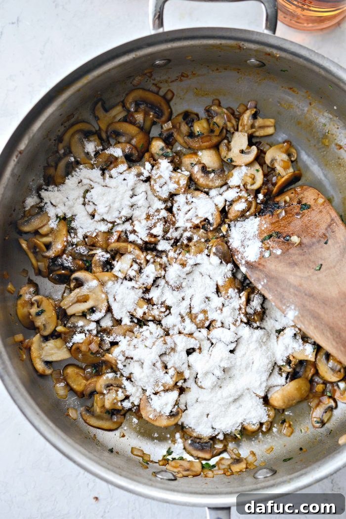 A light dusting of unbleached all-purpose flour sprinkled evenly over the sautéed mushrooms and aromatics in the skillet.