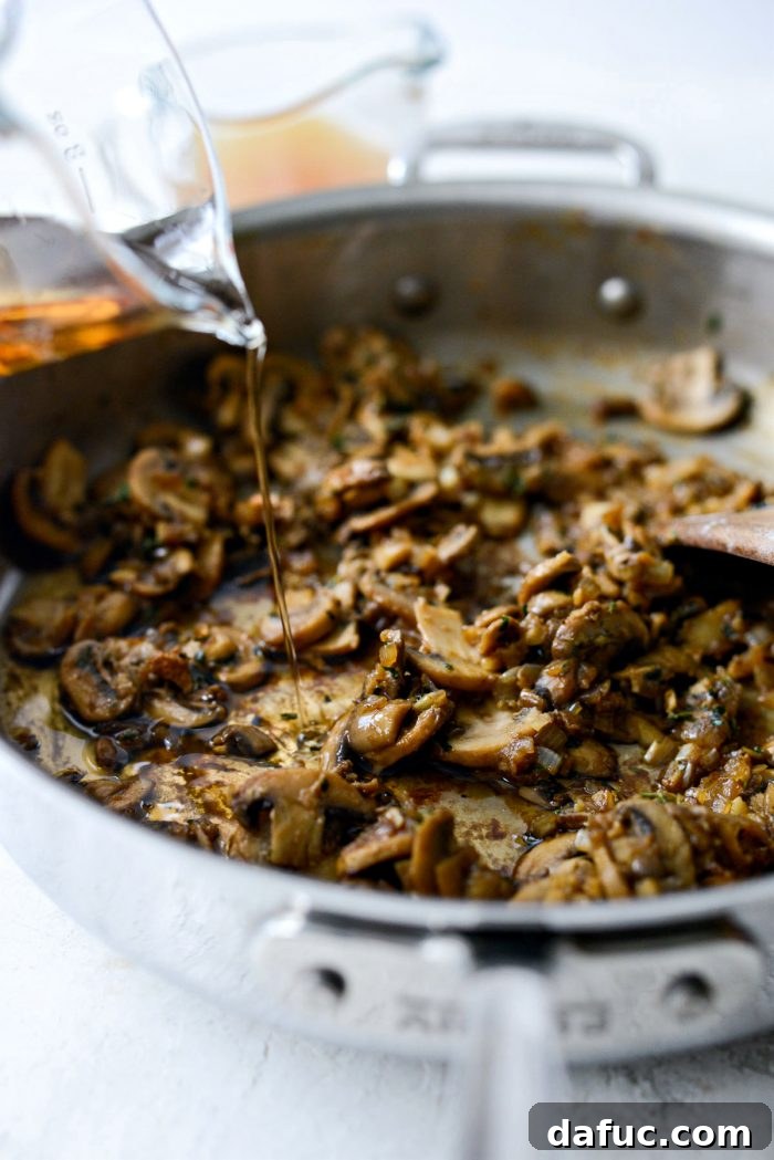 Marsala wine being poured into the skillet with the sautéed mushrooms and flour mixture, beginning the deglazing process.