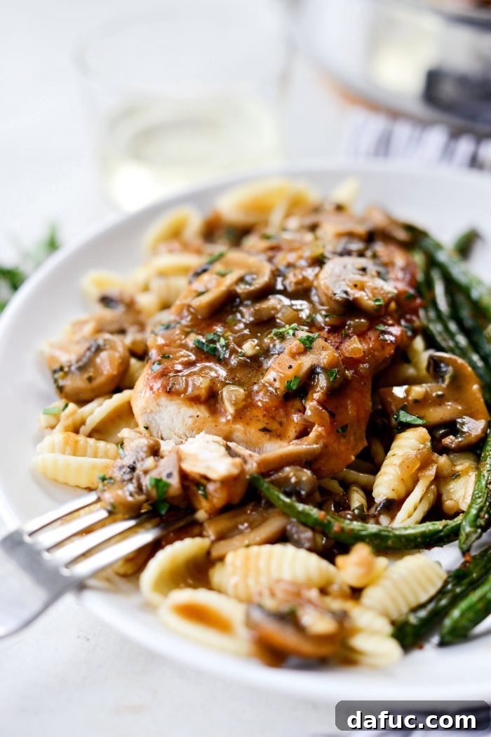 A fork holding a bite-sized piece of Lighter Chicken Marsala, ready to be enjoyed, showing the delicious texture.