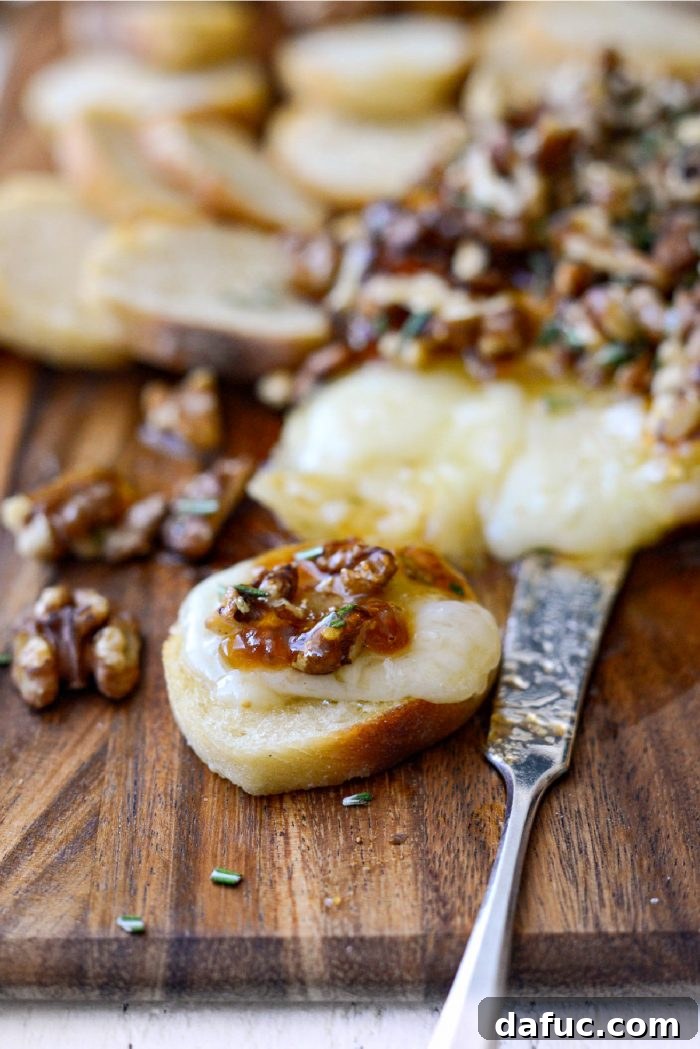 Serving a spoonful of Honey Baked Brie with fig jam onto a crostini.