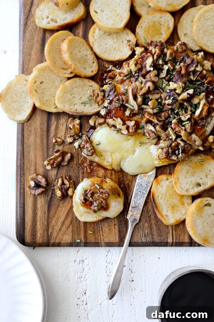 Close-up of a spread of honey baked brie, fig jam, and walnuts on a garlic crostini.