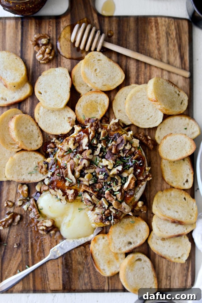 Honeyed Fig and Walnut Baked Brie 18 Beautifully garnished Honey Baked Brie on a dark background, ready to be enjoyed.