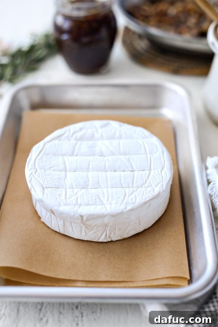 Top of brie cheese being scored with a knife before baking.