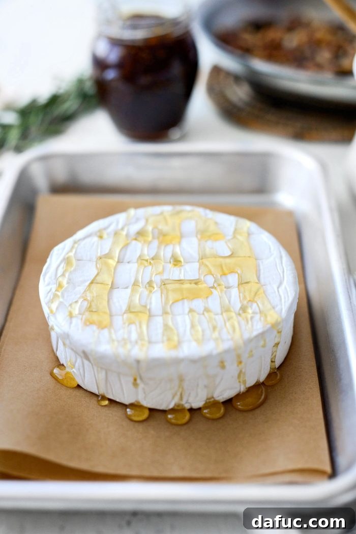 Brie cheese drizzled with honey, ready for baking.