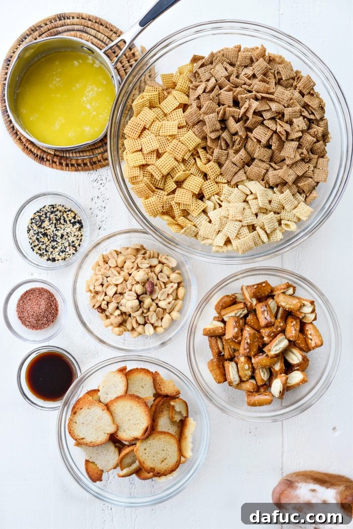 The Ultimate Everything Bagel Chex Mix 4 Close-up of the essential ingredients for Everything Plus The Bagel Chex Mix laid out: unsalted butter, Worcestershire sauce, homemade everything seasoning, various Chex cereals, plain bagel chips, sourdough pretzel nuggets, and roasted peanuts.