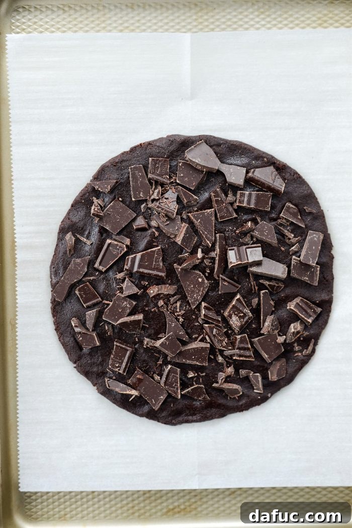 Cookie dough shaped into a disc and topped with chopped dark chocolate